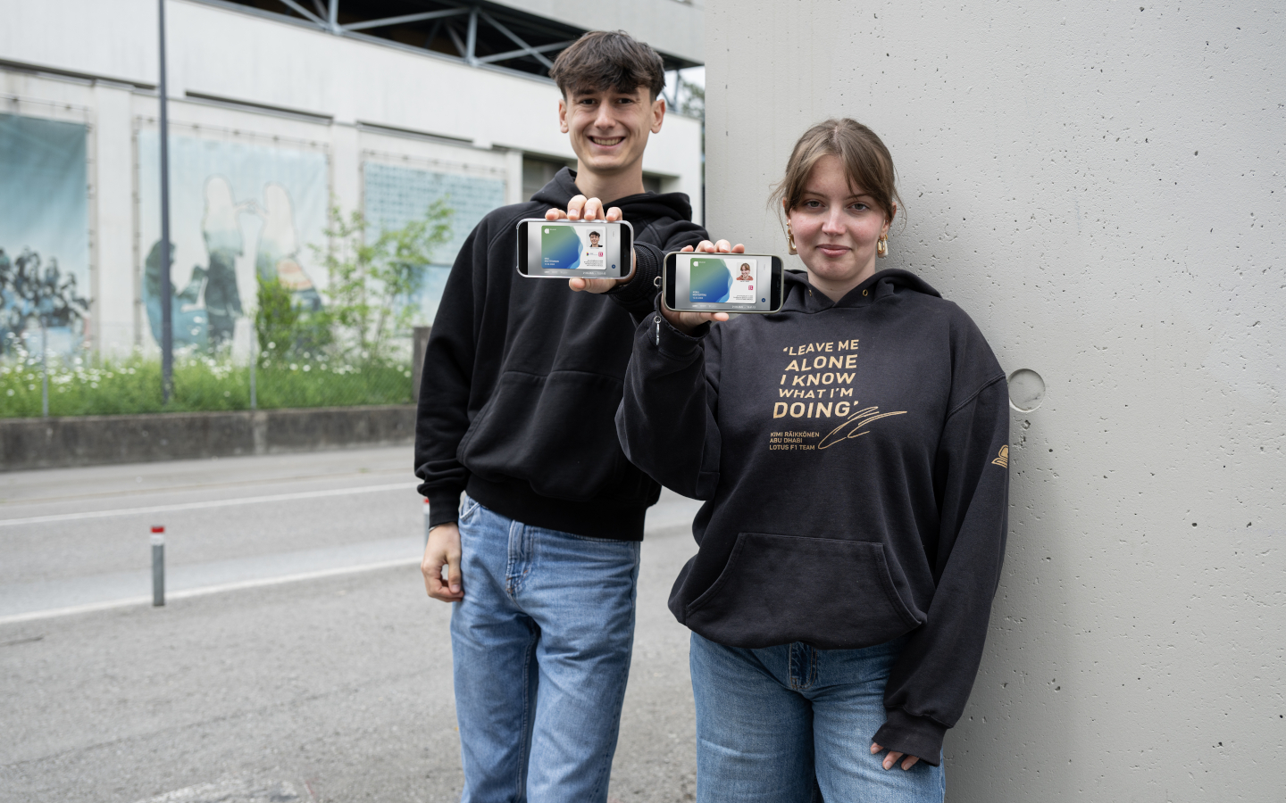 Zwei Jugendliche sitzen in Dornbirn am Marktplatz und strecken ihre aha App am Smartphone in die Kamera